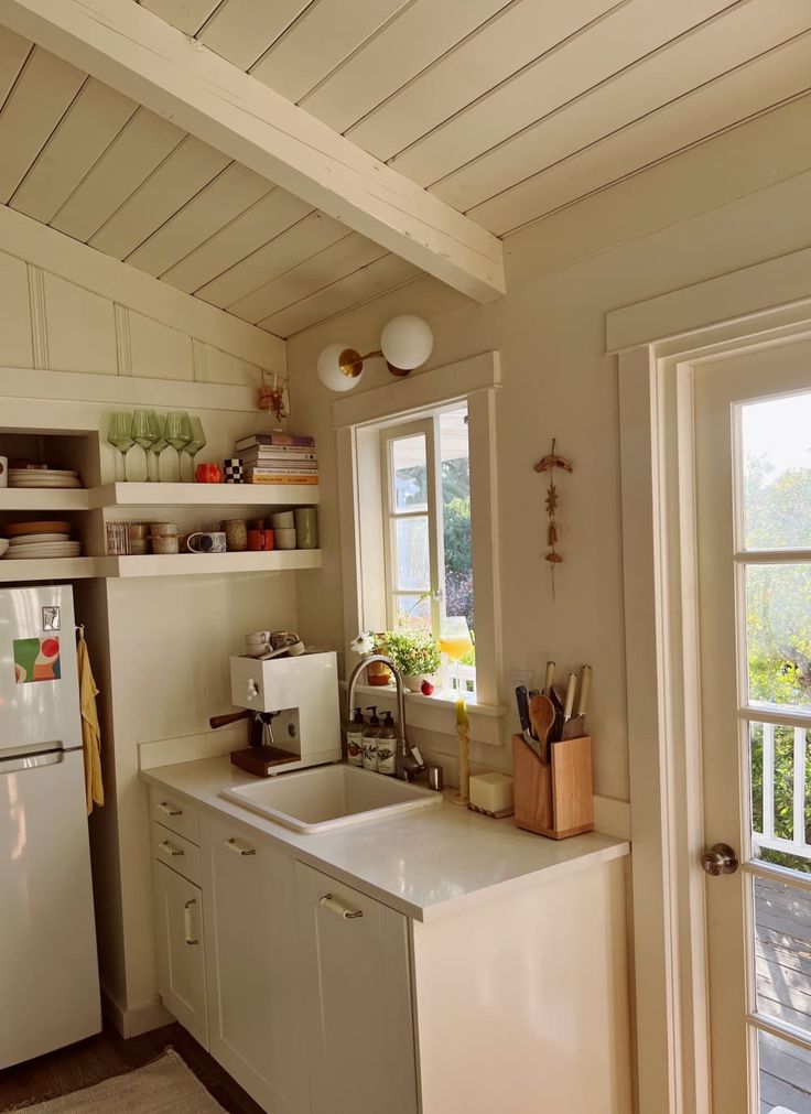 a kitchen with a sink, stove and refrigerator in it's center island next to an open door