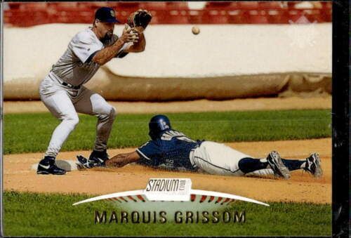 a baseball player sliding into home plate with the ball in his hand and another person laying on the ground behind him