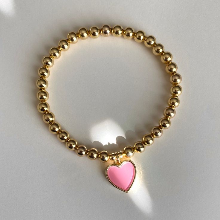 I love this heart charm! Available in pink or pearly white, with 5mm gold filled beads. Charm is 18mm x 12.8mm. This listing is for 1 bracelet only and 5mm gold-filled beads only. Gold-filled beads should not tarnish or fade if handled with proper care. Please read care instructions below. No exchanges or returns. Please contact me anytime with any questions regarding your order. Please measure your wrist before you order, I will not be able to exchange for different sizes at this time. Bracelet Valentine's Day Pearl Bracelet With Heart Charm, Valentine's Day Heart Charm Pearl Bracelet, Valentine's Day Heart Pearl Bracelet, Elegant Pink Beaded Bracelet With Heart Charm, Dainty Pink Heart Charm Bracelet, Gold Beaded Heart Bracelet For Valentine's Day, Dainty Heart Charm Bracelet With Round Beads, Heart-shaped 8mm Bead Jewelry Gift, Pink Heart Bracelet With Round Beads And Heart Charm