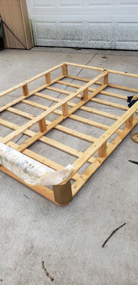 an unfinished bed frame laying on the ground