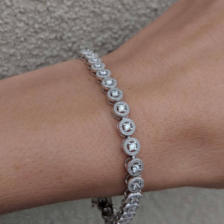 We took a classic tennis bracelet and added vintage charm with delicate milgrain detailing. The bracelet is finished with a box clasp with locking hinge for added security. This bracelet is fully customizable. If you prefer 18k gold or platinum, different dimensions, different quality diamonds or moissanites or colored gemstones, please contact us: http://etsy.me/1231fkN Details: - Solid 14k yellow or white gold - Bracelet is 7 inches in length. For different lengths, please contact us. - SI+G/H Classic Bezel Setting Tennis Bracelet For Formal Occasions, Timeless Round Tennis Bracelet With Diamond Accents, Classic Tennis Bracelet In Diamond White With Diamond Cut, Classic Round Diamond Cut Tennis Bracelet, Classic Round Tennis Bracelet With Diamond Cut, Heirloom Diamond Bracelet With Accents For Formal Occasions, Classic Cubic Zirconia Jewelry, Classic Oval Tennis Bracelet With Prong Setting, Timeless Oval Tennis Bracelet With Prong Setting