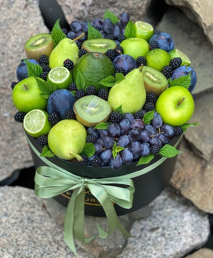 a bunch of fruit is sitting in a black box on the ground next to some rocks