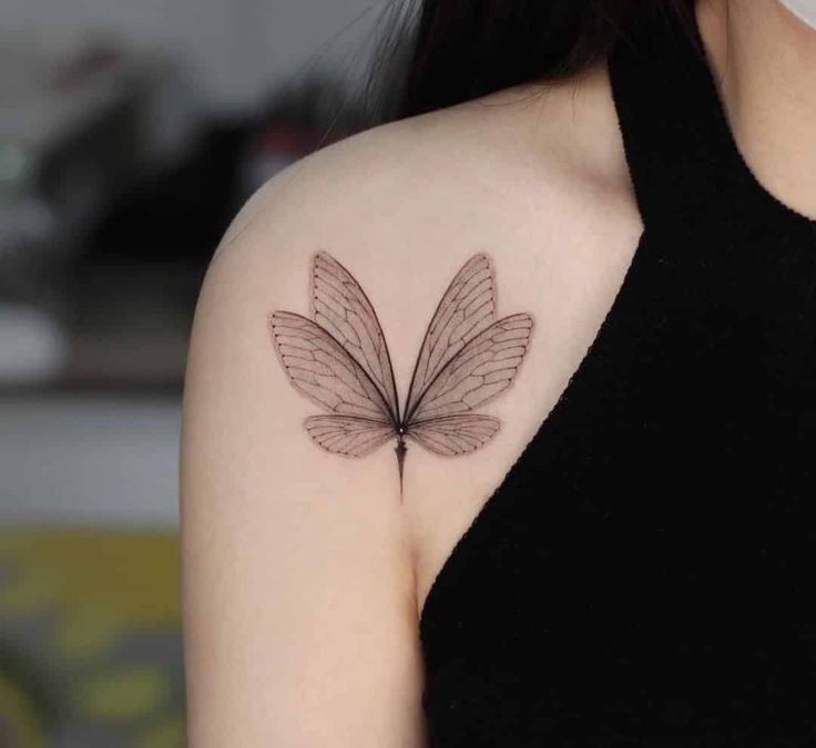 a woman with a butterfly tattoo on her left shoulder and chest, in black ink