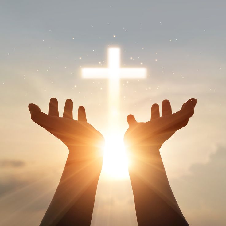 someone holding their hands in front of a cross with the sun shining behind them,