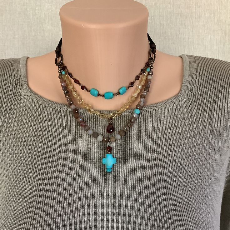 Gladness Enhance your jewelry collection with this Sundance Style gemstone layered necklace.  This unique piece features a beautiful combination of mixed gemstones including elegant garnet, amazing citrine, sparkling aqua neuvo agate, stunning turquoise magnesite and turquoise, creating a rich and colorful palette.   The delicate sprinkling of mixed metals adds a trendy touch while the adjustable real leather lace ensures the perfect fit for any outfit.  At each end of the leather is a small turquoise bead. Adorned with turquoise cross and garnet CZ pendants, this necklace adds a touch of elegance and spirituality and becomes a true statement accessory.  It will make a thoughtful and unique gift for yourself or a loved one who appreciates artisanal jewelry.  Elevate your look and bring a t Bohemian Multi-strand Adjustable Turquoise Necklace, Adjustable Multi-strand Bohemian Turquoise Necklace, Artisan Turquoise Multi-strand Necklace, Sundance Style, Silver Southwestern Multi-stone Turquoise Necklace, Bohemian Turquoise Multi-stone Pendant Necklace, Handmade Boho Jewelry, Turquoise Cross, Cz Pendant