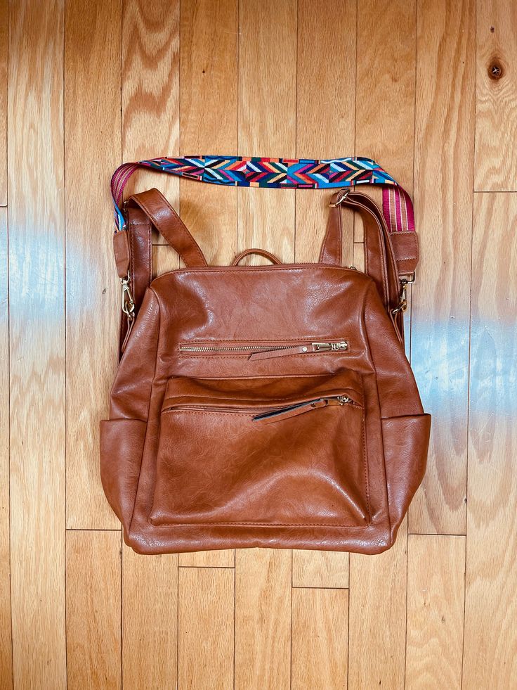 Classy & verstile butterscoth brown pleather bag that can be worn as a backpack, top handle, and shoulder bag.  Terrific, unique butterscotch color that goes with everything. Gold tone hardware.  Removable long shoulder strap has wide & flat fabric that's reversible, with a different pattern on each side. One side is a colorful geometric pattern that looks Southwestern. The opposite side is a peach & butterscotch brown striped Preppy pattern. The wide flat strap makes any weight super comfy on t Brown On-the-go Bag With Adjustable Straps, Brown Satchel With Large Capacity, Brown Double Handle Satchel For School, Brown Softback Satchel With Large Capacity, Brown Leather Backpack With Adjustable Strap For On-the-go, Brown School Bag With Zipper Closure, School Bag With Zipper In Brown, School Bag With Zipper Closure In Brown, Brown Leather Backpack With Zipper For Daily Use