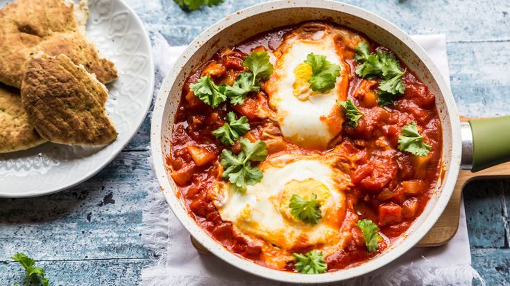 two plates with eggs and some bread on the table next to each other, one has an egg in it