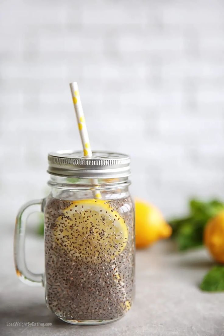 a mason jar filled with chia seeds, lemons and a straw sticking out of it