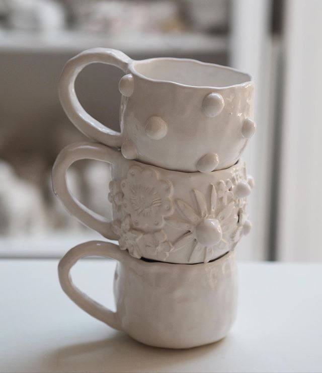 three white coffee cups stacked on top of each other with flowers and dots in them