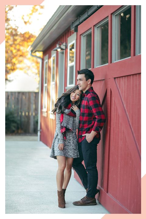 a man and woman leaning against a red wall