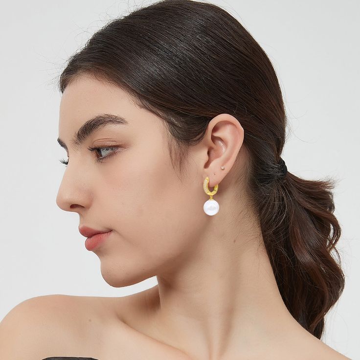 This pair of earrings features a lustrous solitaire shell pearl and a radiant gold hoop, creating a harmonious balance of classic and modern. The delicate huggie hoop is adorned with brilliant pavé set zirconia, adding a touch of sparkle and glamour that beautifully complements the pearls. These earrings effortlessly transition from day to night, from casual to formal events. Whether you're attending a wedding, a dinner party, or simply adding a touch of luxury to your everyday attire, these ear Modern Yellow Gold Hoop Earrings With Pearl Drop, Modern Hoop Jewelry With Pearl Charm, Modern Hoop Earrings With Pearl Charm, Modern White Pearl Hoop Earrings, Modern White Huggie Earrings For Everyday, Modern Round Pearl Earrings With Pearl Charm, Modern Gold Hoop Earrings With Pearl Charm, Modern White Single Pearl Earring, Modern White Round Pearl Earrings