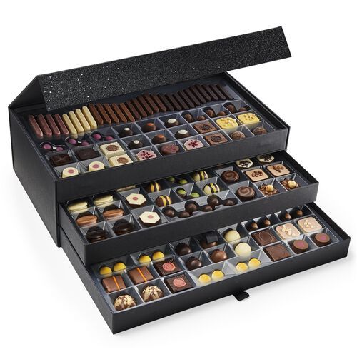 an assortment of chocolates is displayed in a black box on a white background with the lid open