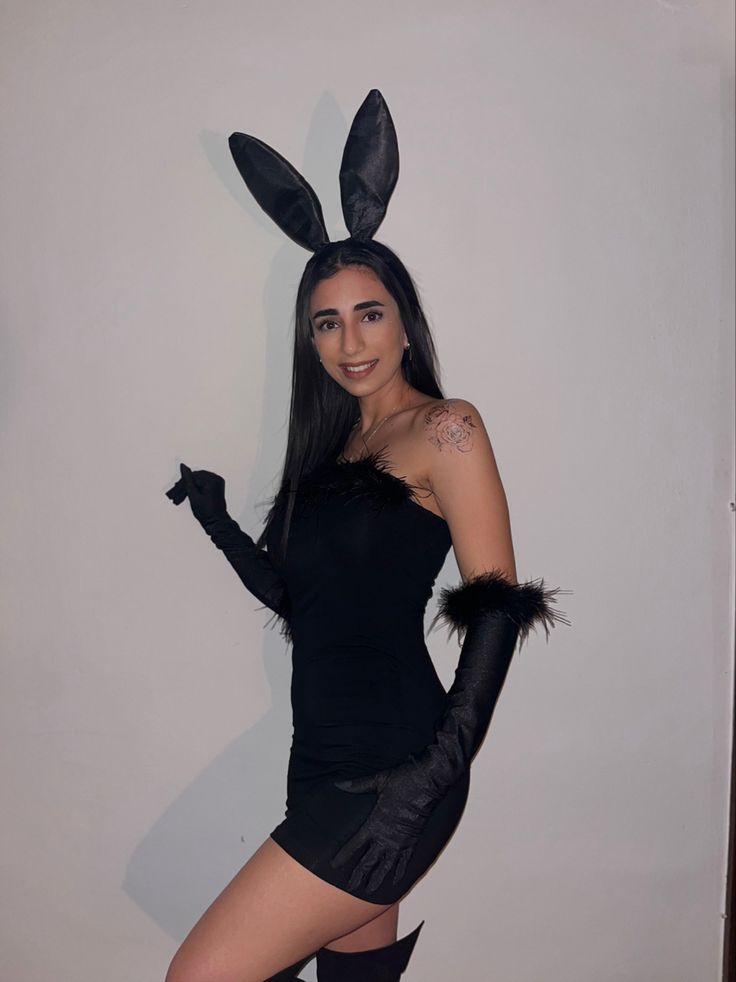 a woman in bunny ears and black dress posing with her legs spread out, wearing thigh high boots