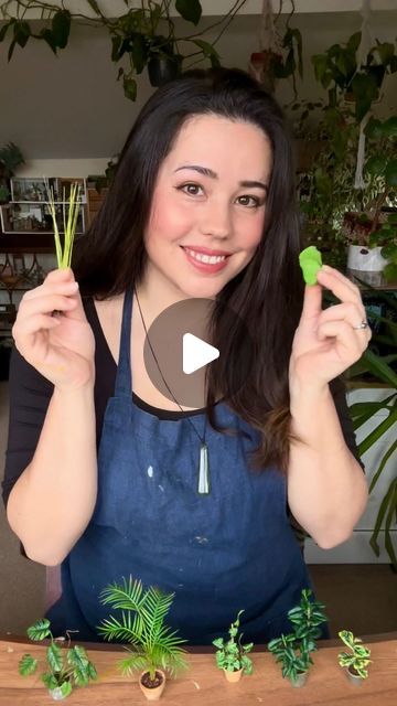 a woman is holding up two plants in front of her face and smiling at the camera