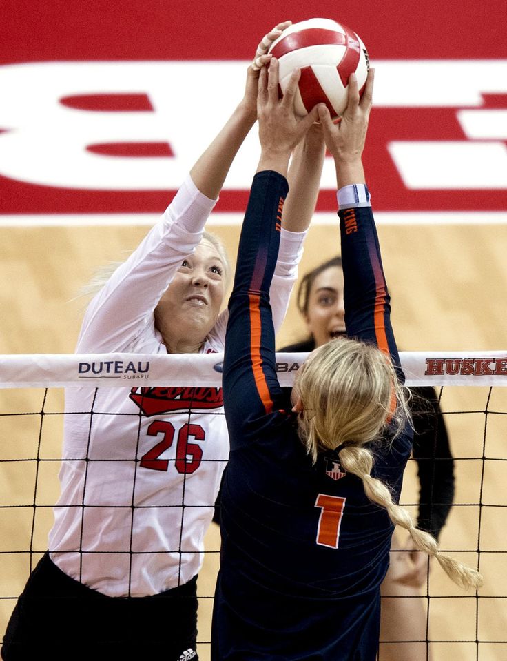 two female volleyball players trying to block the ball