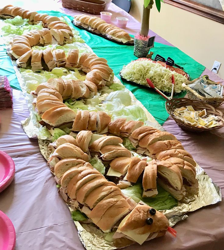 a table topped with lots of sandwiches and other food