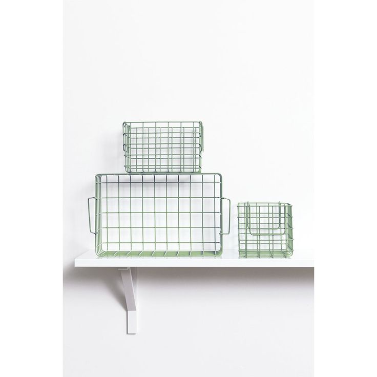 three green wire baskets sitting on top of a white shelf next to each other in front of a white wall