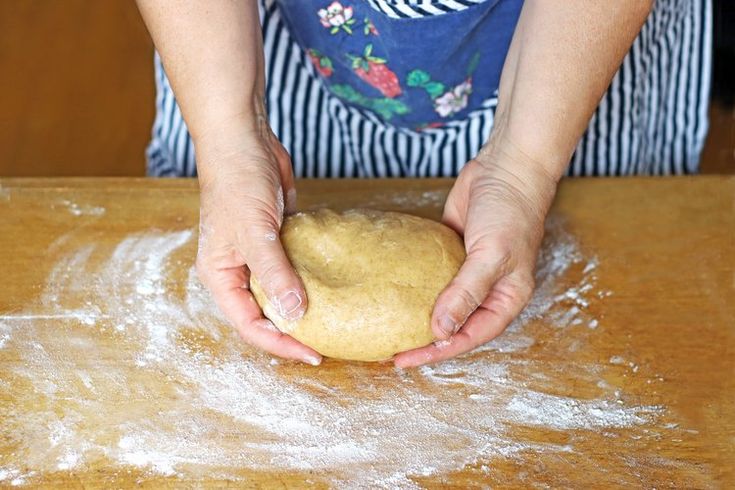 a person kneading dough on top of a wooden table