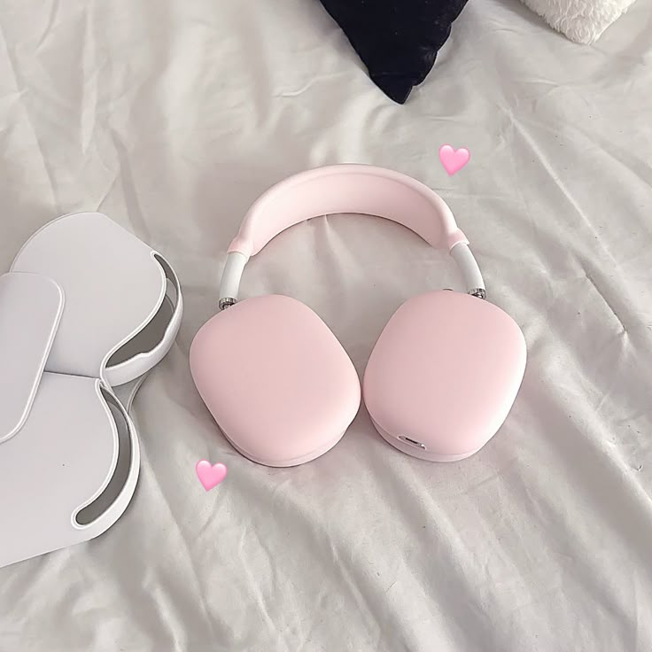 two pink headphones sitting on top of a white bed