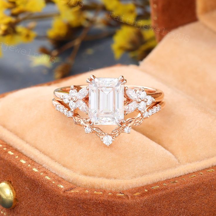 a ring with an emerald stone surrounded by diamonds on top of a brown velvet box