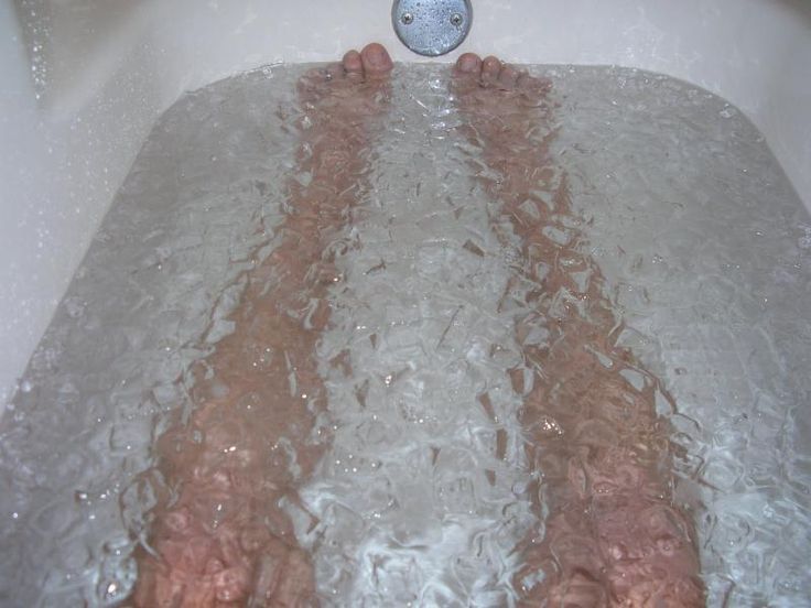 two people are laying in the bathtub with their feet on the faucet