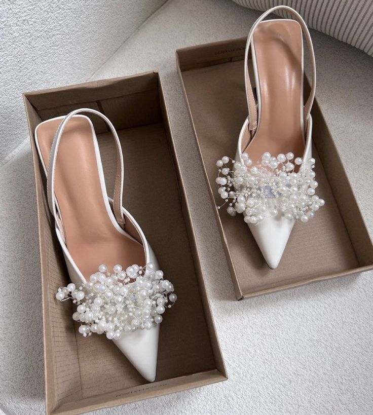 two pairs of white shoes with pearls on the heel and one pair is in a box