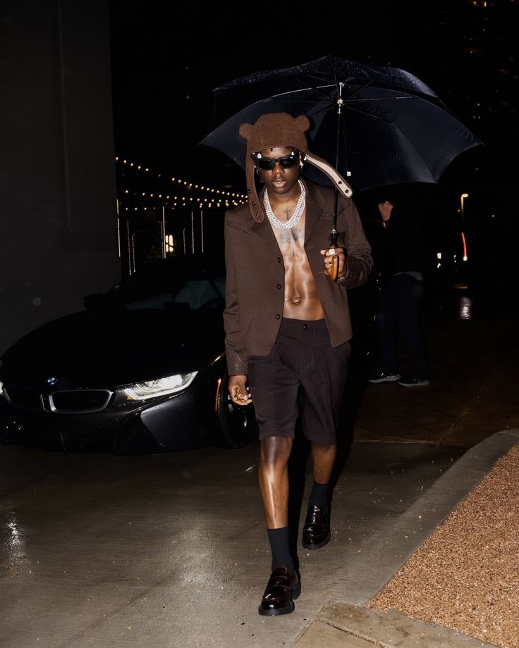 a man walking down the street with an umbrella over his head and sunglasses on top of his head