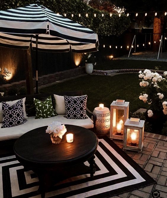 an outdoor living area with candles lit on the table and couches in the background