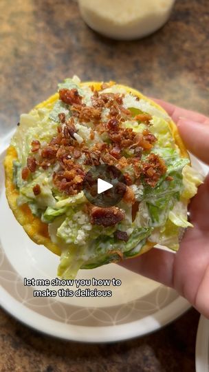 a person is holding up a food item with bacon on top and lettuce in the middle