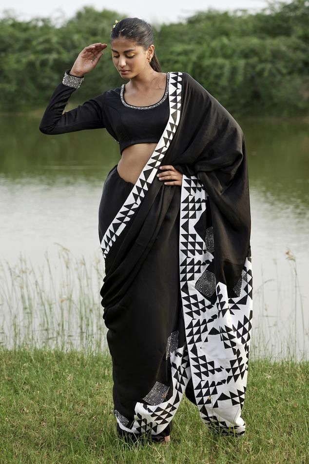 Black saree in taffeta base with black and white prism print on the pallu. Paired with long sleeves embellished neckline padded blouse.
Components: 2
Pattern: Print
Type Of Work: Prism
Neckline: Scoop
Sleeve Type: Full
Fabric: Taffeta
Color: Black
Other Details: 
Attached lining
Padded blouse
Model height: 5ft 8inches, wearing size S
Length:
Blouse: 14inches
Saree: 45inches
Disclaimer: This product is exclusively hand crafted using multiple techniques, individually handled at different stages, a Bollywood Style Black Cotton Silk Pre-draped Saree, Black Cotton Silk Saree Blouse Piece, Festive Black Cotton Silk Pre-draped Saree, Black Georgette Blouse With Mirror Work, Semi-stitched Black Cotton Silk Blouse Piece, Designer Black Blouse With Mirror Work, Black Cotton Silk Pre-draped Saree, Black Block Print Saree With Traditional Drape, Unstitched Black Saree With Block Print