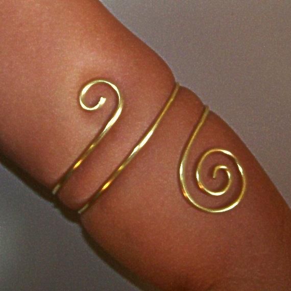 This armlet has been created using thick 12 gauge brass. This armlet wraps twice around the arm and is adorned with a small swirl on the top and a larger swirl on the bottom. ♥These are available in brass, bronze, copper and German silver. Please note that German silver contains nickel and contains no silver, but is lead free. Please Note: When measuring your lower arm for this piece...be sure the size you choose is the thickest part of the arm it will sit, as this piece is slightly tapered. if Handmade Flexible Gold Bracelet, Gold Handmade Flexible Bracelet, Wire Wrapped Gold Bracelets For Festival, Gold Wire Wrapped Bracelets For Festivals, Gold Wire Wrapped Bracelet For Festival, Upper Arm Jewelry, Gold Arm Cuff, Upper Arm Bracelet, Gold Arm Band