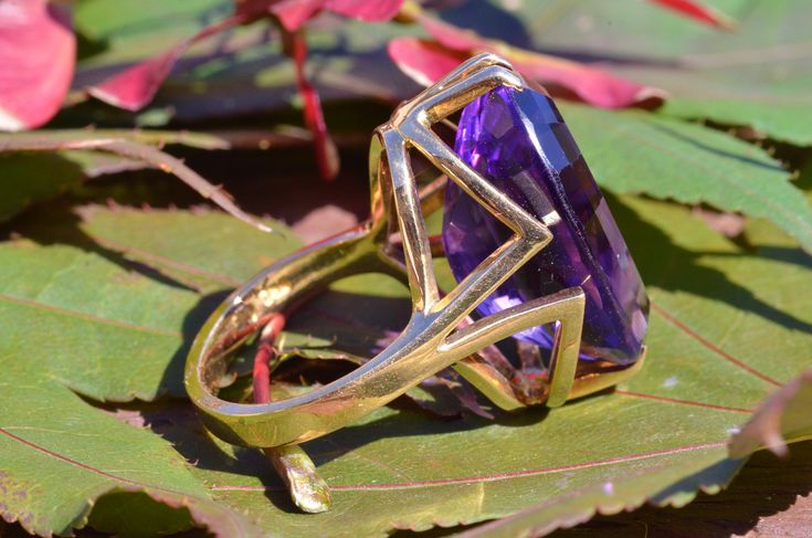 "The Brookside Outstanding Amethyst Cocktail Ring. The ring features an amazing, over 20 carat oval brilliant cut vivid purple amethyst in the center. Finished with a mid century modern filigree type shank in the through finger view the ring makes a statement. The ring is crafted in 18 karat yellow gold and is signed by the designer with the hallmark \"CB\" Yet we have not quite identified the craftsman quite yet. An amazing statement piece and a benchmark for the mid century modern era. Each pi Luxury Faceted Amethyst Ring For Formal Events, Luxury Faceted Amethyst Ring For Formal Occasions, Formal Faceted Purple Amethyst Ring, Faceted Purple Amethyst Ring For Formal Occasions, Formal Faceted Amethyst Ring, Formal Faceted Purple Ring, Purple Faceted Ring For Formal Occasions, Modern Amethyst Ring As Gift, Formal Purple Faceted Ring