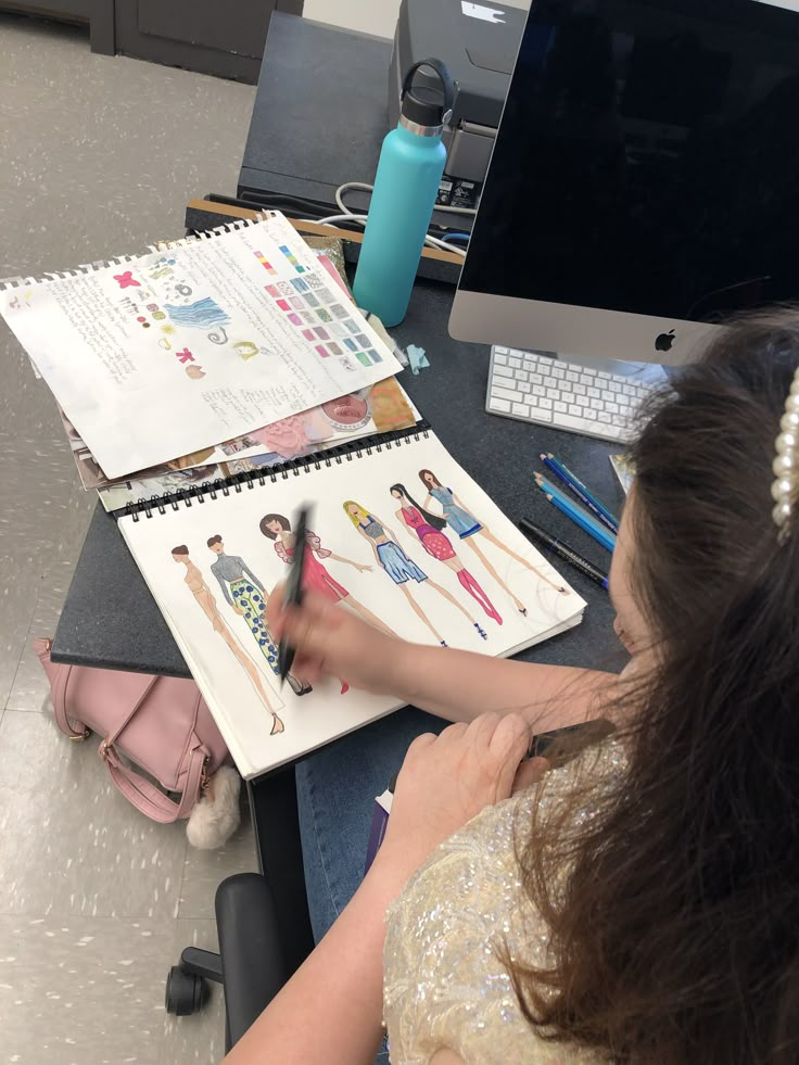 a woman sitting at a desk drawing on paper