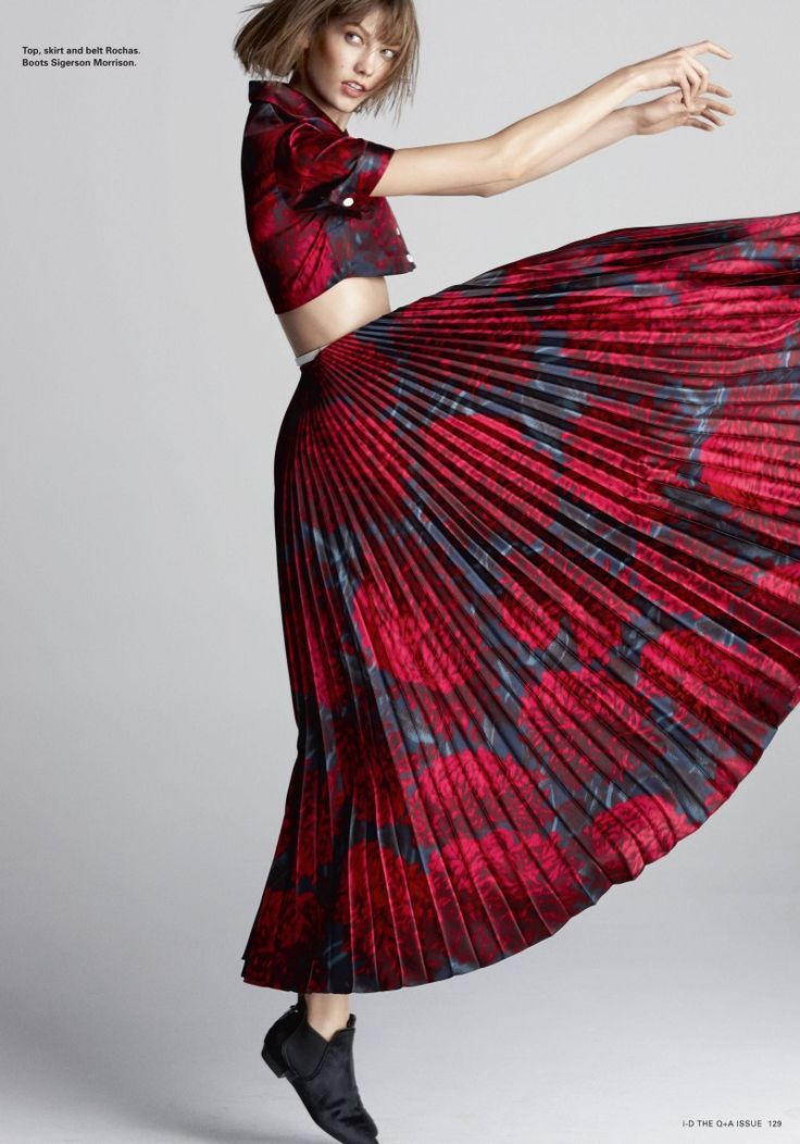 a woman in a red and black dress is posing with her arms out to the side