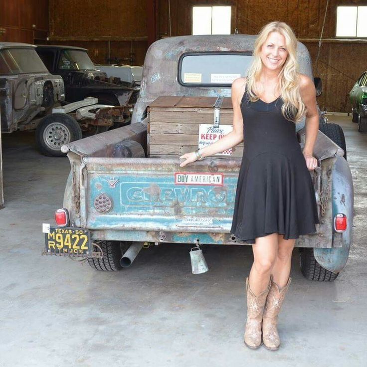 a woman standing next to an old truck