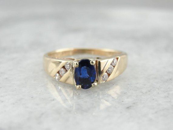 Simple, refined and set low to the hand, this vintage sapphire ring would make a great piece for day to day wear. The stone has plenty of shine and a rich color, accented by the simply set diamond shoulders.Metal: 14K Yellow GoldGem: Sapphire .48 CaratGem Measurements: 4 x 5.8 mm, Oval Accent: 6 Diamonds .18 CaratRing Size: 4.75Marks: "O14KT<>61B"Stamped on the inside band SKU: 65UE3E-DEach piece has been identified and graded by a Graduate Gemologist who has been certified by the Gemologi Formal Sapphire Ring With Diamond Side Stones, Classic Sapphire Ring With Channel Set, Classic Sapphire Ring With Side Stones For Anniversary, Vintage Sapphire Ring, Vintage Sapphire, Ladies Ring, Eternity Bands, New Hampshire, Deep Blue