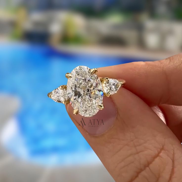 a close up of a person's hand holding a ring with three diamonds on it