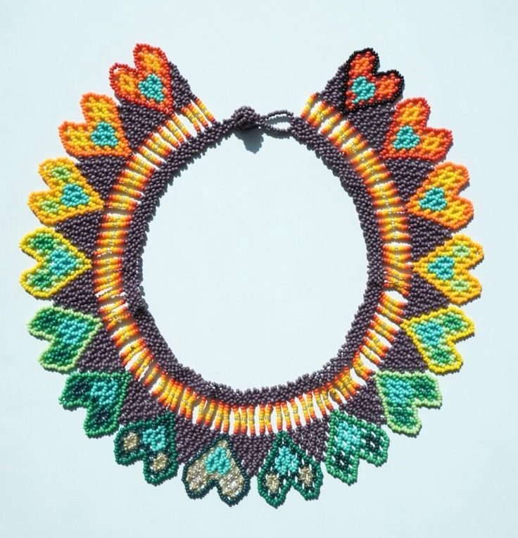 a beaded bracelet with multicolored beads and leaves on the front, sitting on a white surface