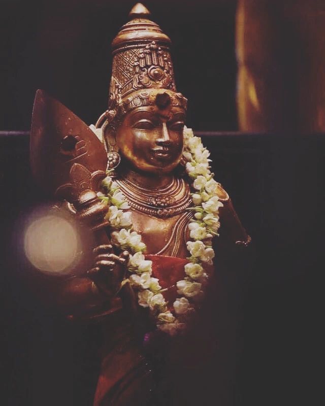 a statue with flowers around it's neck and a light in the back ground