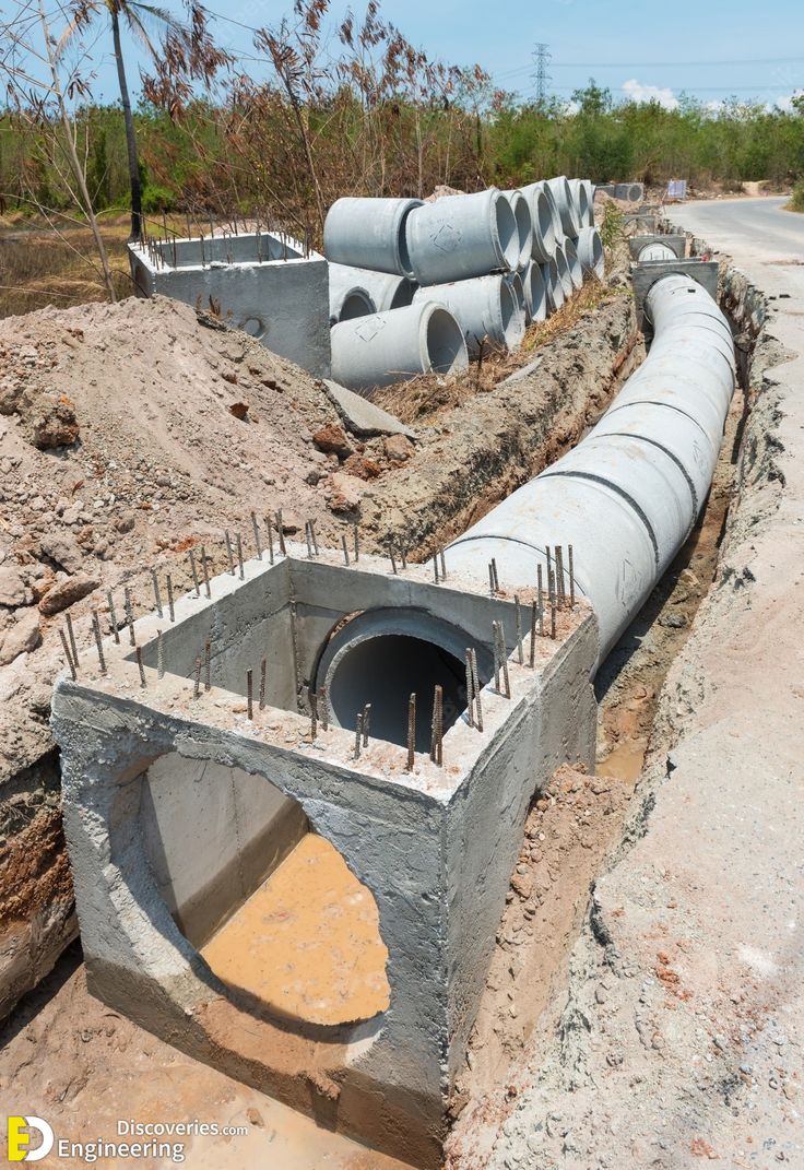 concrete pipes are lined up in the middle of a construction area with dirt and rocks