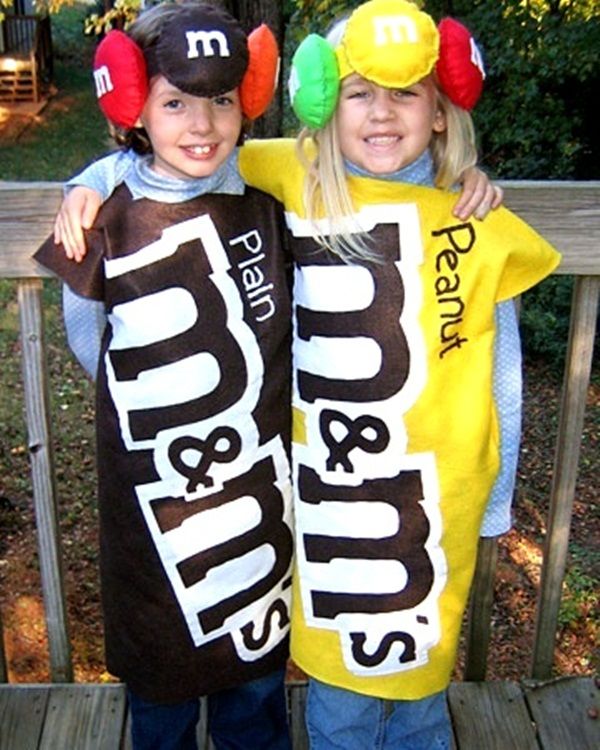 two children dressed up in costumes standing on a wooden deck with their arms around each other