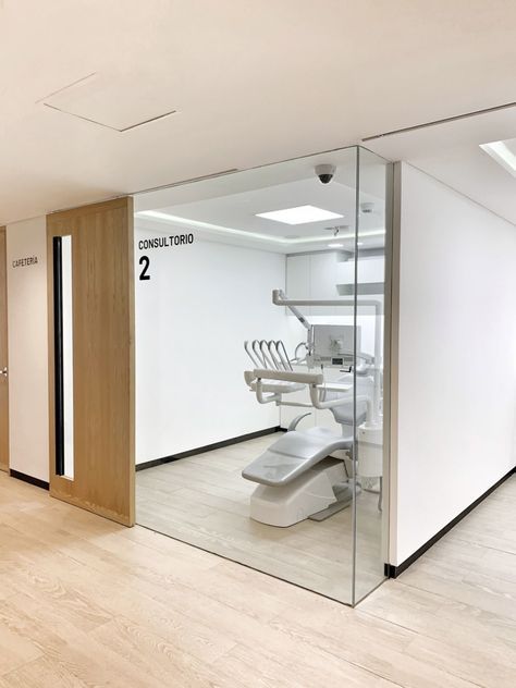 an empty dental office with glass walls and white fixtures on the wall, along with wooden flooring