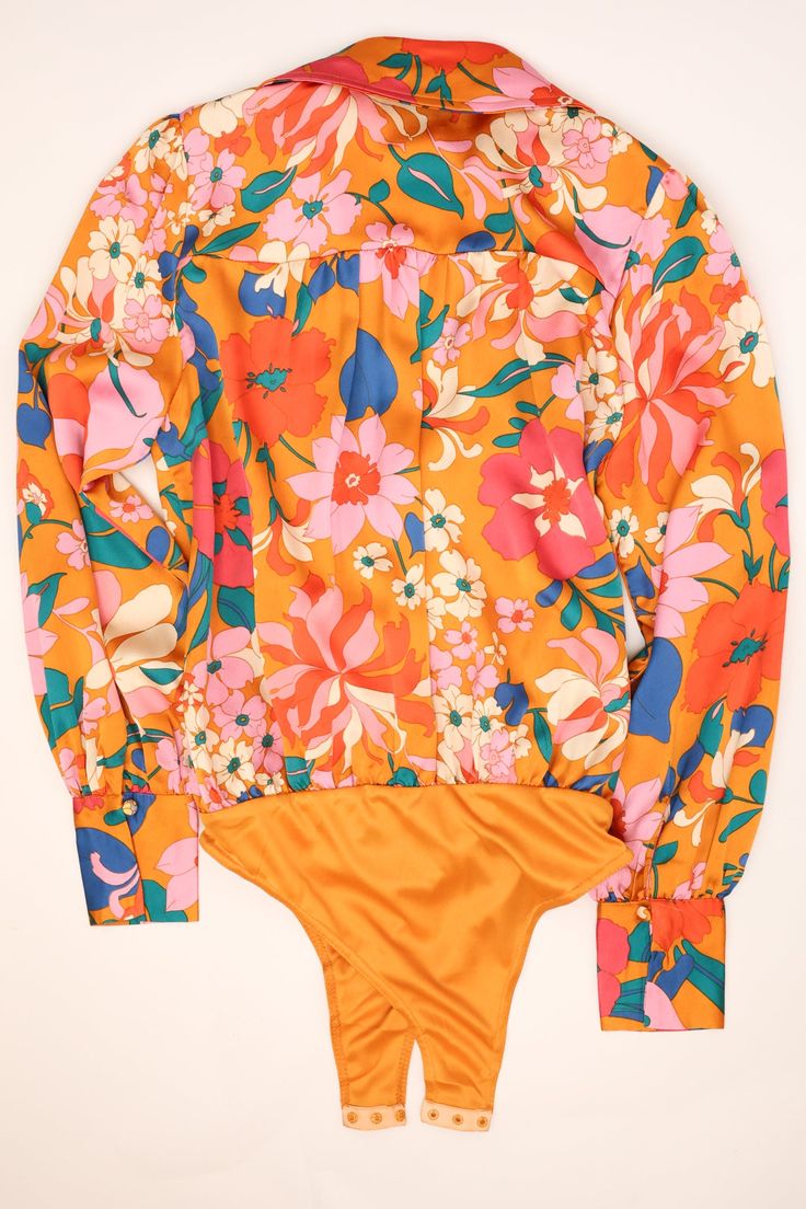 This is the bodysuit of your dreams! It's so chic and classy! The floral print is wonderfully bold and that satin fabric couldn't be more luxurious! This bodysuit is going to be a fab choice for any day at the office and then for drinks after! Surplice v-neckline Long bubble sleeves Bold floral print Cheeky bottoms with button snap closure No stretch London is wearing the small. Summer Orange Floral Print Swimwear, Multicolor Floral One-piece Bodysuit, Orange Floral Print Swimwear, Fitted Playful Floral Print Swimwear, Orange One-piece Swimwear With Floral Print, Floral Bodysuit, Bold Floral Print, Mint Julep Boutique, Mint Julep