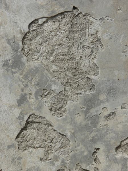 an old cement wall with holes and cracks in the concrete, as well as paint on it