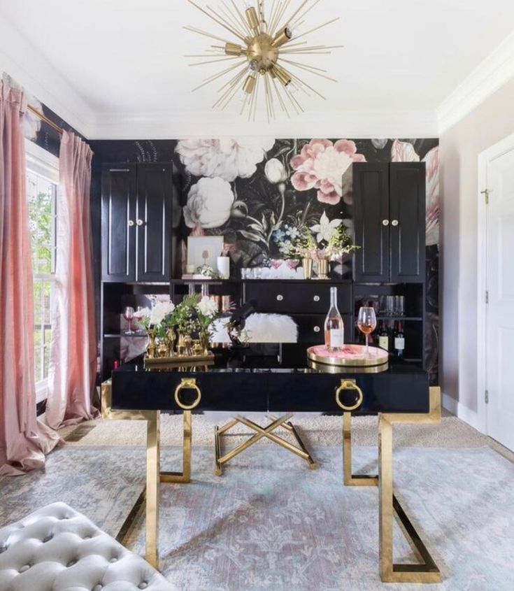 a black and gold living room with floral wallpaper on the walls, chandelier and couch