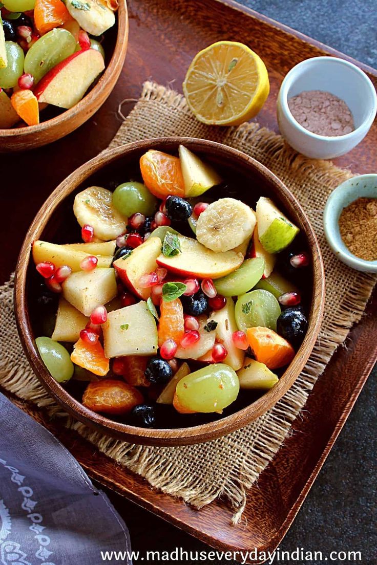 two bowls filled with fruit on top of a wooden tray