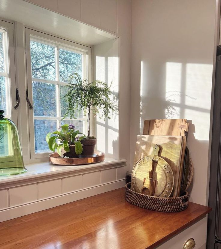 a wooden counter top sitting under a window next to a potted plant and clock