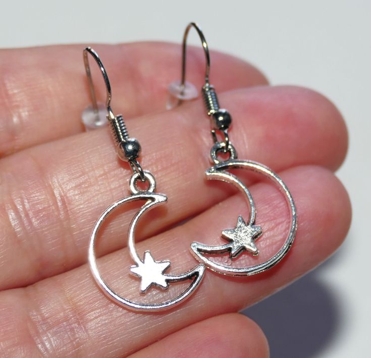 "Crescent moon star earrings. Antique silver tone crescent moon and star charms dangling from hypoallergenic steel hooks with rubber backs. Earring length: 37mm, 1.5\" Charm material: zinc alloy, lead free cadmium free This listing is for one pair of mon and star earrings with rubber backs. This earring will come in a gift bag. I offer combined shipping costs which give you a shipping discount for ordering multiple items from my shop. Earrings care: Take them off while you sleep, sports activiti Silver Star-shaped Hoop Earrings, Silver Star Charm Earrings In Stainless Steel, Adjustable Silver Celestial Hoop Earrings, Silver Crescent Earrings With Star Charm, Nickel-free Metal Star Earrings, Nickel-free Star Shaped Metal Earrings, Nickel-free Star-shaped Metal Earrings, Silver Stainless Steel Star Charm Earrings, Silver Stainless Steel Earrings With Star Charm