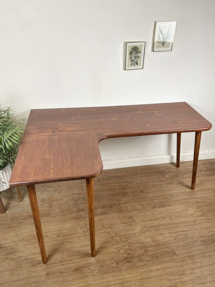 a wooden table sitting on top of a hard wood floor next to a potted plant