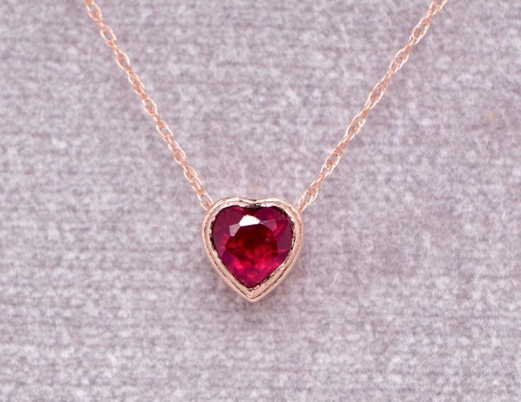 This stunning necklace is made with 14k rose gold and encases an earth mined ruby, the birthstone of July. Dusted with moissanite for a little bit of style, this versatile necklace easily transitions from business casual to a little sparkle on a night out. Also great for layering if you want extra sparkle!  A statement in elegance these are simply perfect for those who like to make a small statement.  Perfect for brides, anniversary gifts or for a birthday gift to someone special.  Length : 16 inches Metal : 14kt Rose Gold  Gemstones : Earth Mined Ruby, Lab Moissanite Packaging : All products purchased from us come in a gift box. If you need to include a message, kindly leave us a note when purchasing.  Care Recommendations:  When not in use, keep earrings enclosed in a box or pouch to min Valentine's Day Gift: Yellow Gold Birthstone Necklace, Gold Birthstone Necklace For Anniversary, Valentine's Day Gift, Valentine's Day Heart-shaped Birthstone Necklaces, Heart-shaped Ruby Necklace For Gift, Personalized Heart-shaped Birthstone Necklace For Valentine's Day, Ruby Heart, July Birthstone, Pink Gemstones, Stunning Necklace